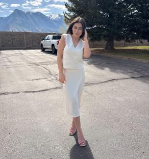 Woman in a white midi skirt and matching top.