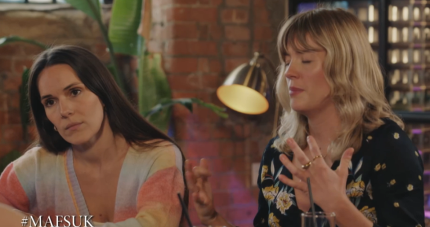 Two women talking, one with long dark hair, the other with blonde wavy hair.