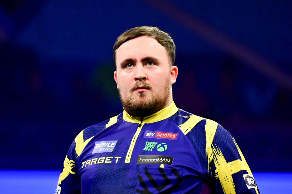 Luke Littler wearing a blue and yellow darts jersey at the World Grand Prix Darts Final.