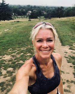 Woman in sports bra smiling at camera in park.