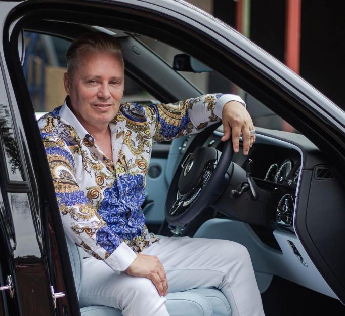 a man in a blue and white shirt is sitting in a car