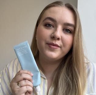 Woman holding a tube of Sunday Riley The Cleanser.