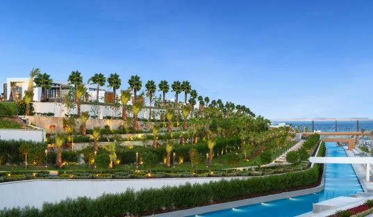 Rixos Radamis resort landscaping with palm trees and a pool.