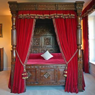 Ornate four-poster bed with red velvet curtains.