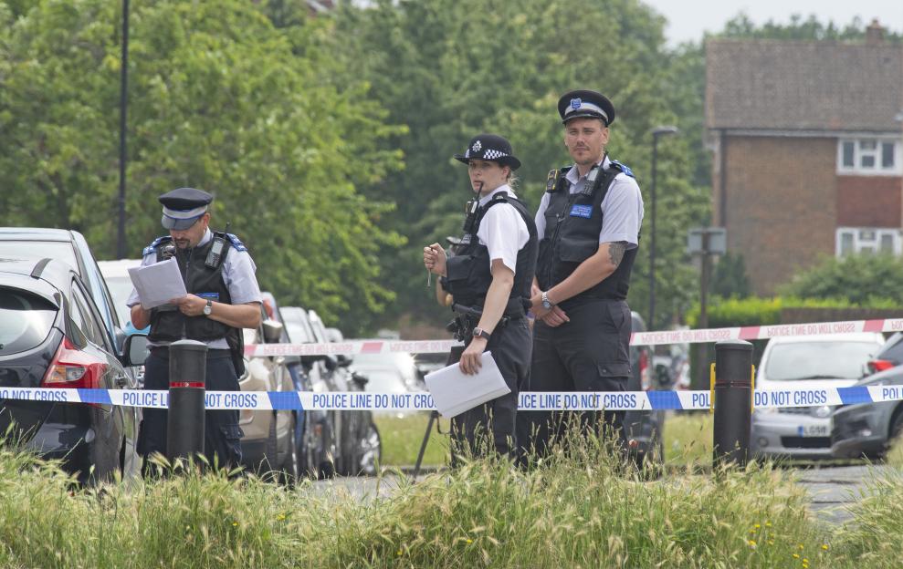 Police officers and a police line in Croydon, UK, after a 16-year-old was stabbed to death.