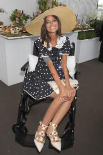 Woman in polka dot dress and wide-brimmed hat sitting in wheelchair at Royal Ascot.