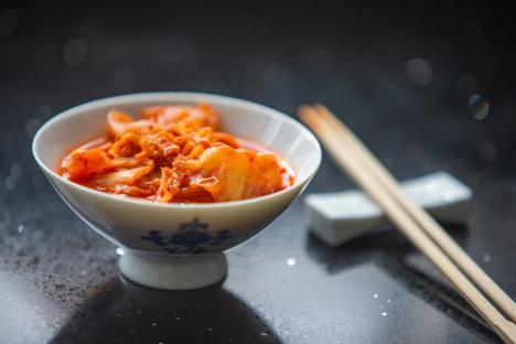 Kimchi in a porcelain bowl with chopsticks.
