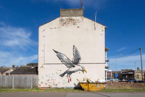 Mural of a herring gull eating chips.