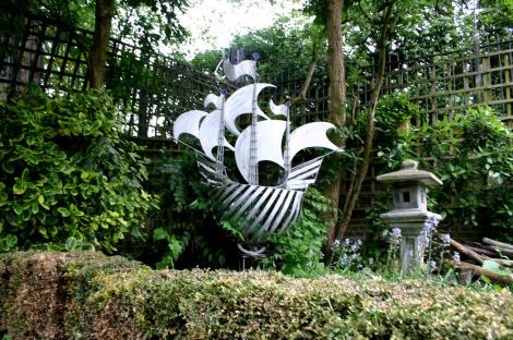 Metal ship sculpture in a garden.