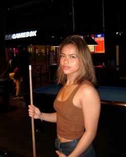 Woman holding a pool cue in a game room.