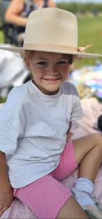 Smiling girl wearing a hat and pink shorts.