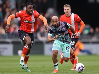 Bryan Mbeumo of Brentford challenged by Pelly Ruddock Mpanzu of Luton Town during a Premier League match.