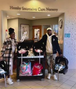 Couple leaving Hemby Intensive Care Nursery with quadruplets in car seats.