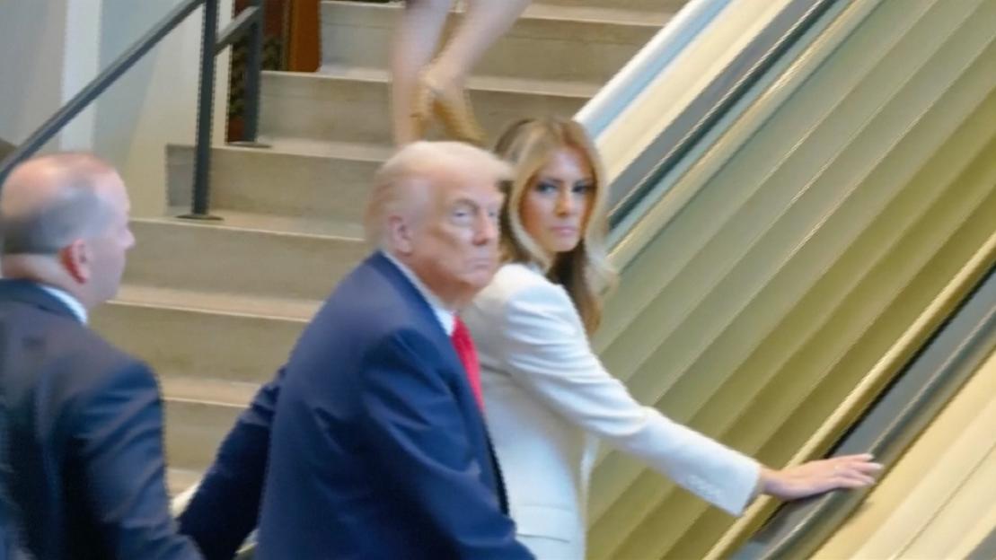 Donald Trump and Melania Trump on an escalator that has stopped.