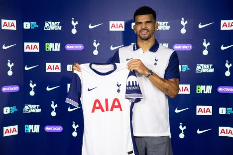 Dominic Solanke holding a Tottenham Hotspur jersey at a press conference.