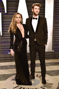 a man in a tuxedo stands next to a woman in a black dress