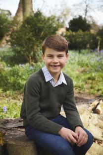 Portrait of a smiling boy sitting on a tree stump.