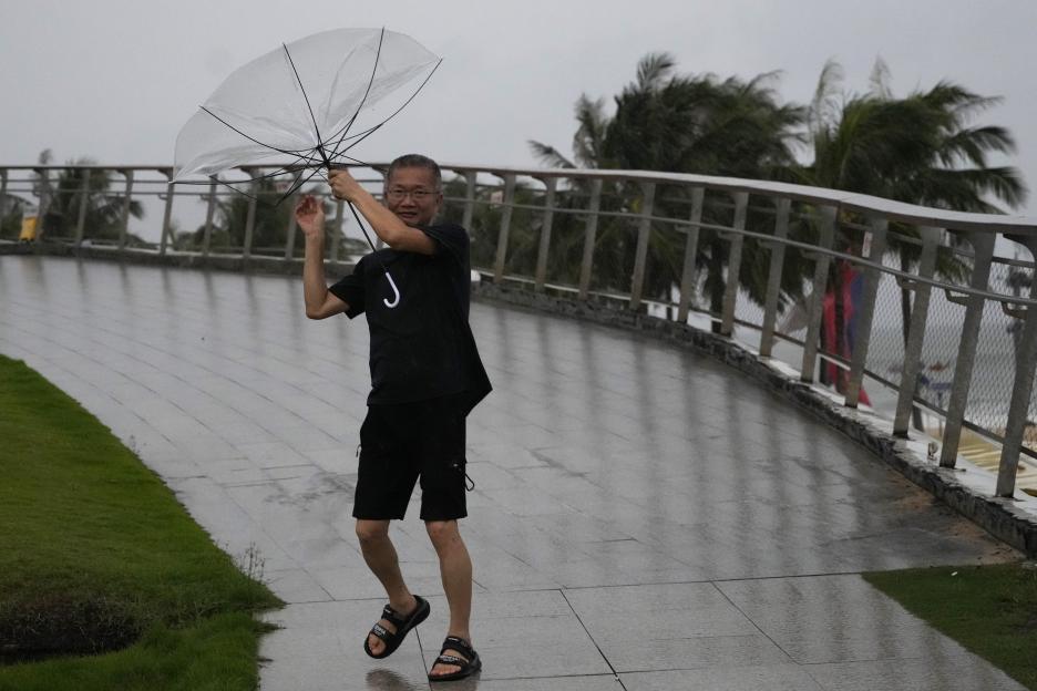 A man struggles to hold onto his umbrella in strong winds.