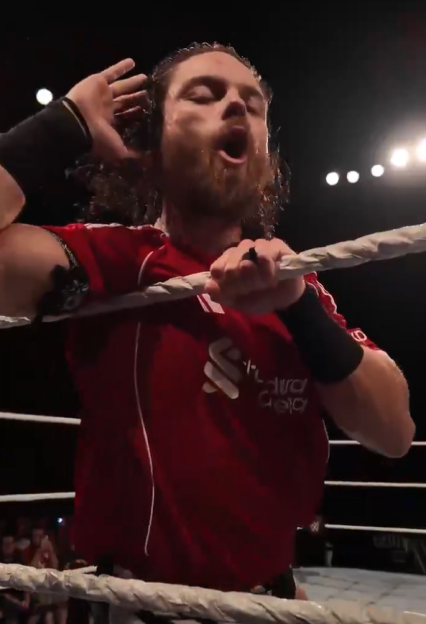 Wrestler in red shirt in a ring.