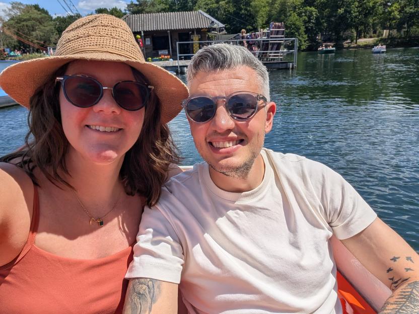 Couple smiling in a boat on a lake.