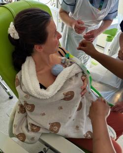 A mother holding her premature baby, who is wrapped in a blanket.