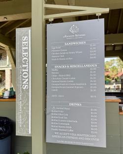 Menu board for the Augusta National Women's Amateur event, listing sandwiches, snacks, and drinks with prices.
