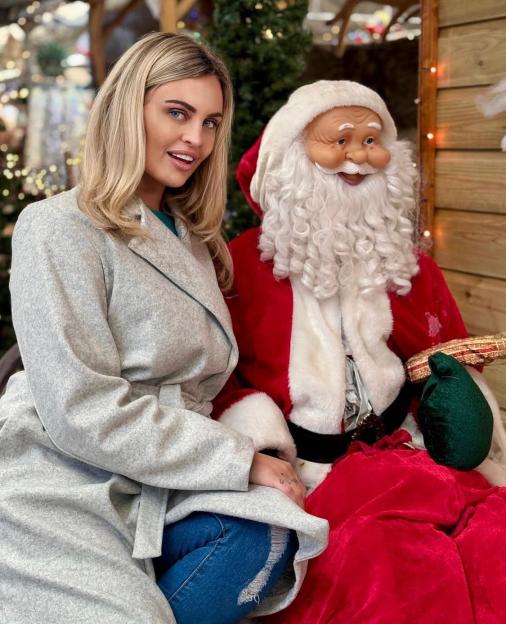 Carla Bellucci sitting next to a Santa Claus figure.