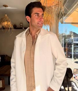 Man in white textured jacket and beige shirt.