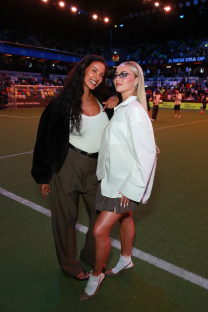 Two women posing on a soccer field.