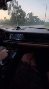 Interior view of a car driving, with a person's legs visible in the passenger seat.