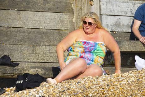 Gemma Collins sitting on a beach.