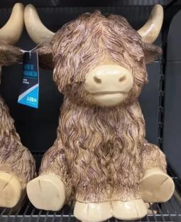Highland cow garden ornaments on a shelf.