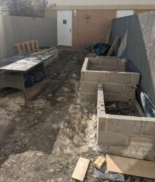 A building site with an unfinished concrete block structure, debris, and tools, showing the state of properties defrauded by Mark Killick.