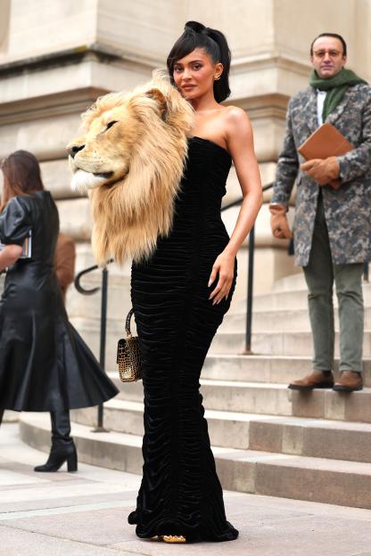 Kylie Jenner wearing a black dress and a lion head as a shoulder piece at Paris Fashion Week.