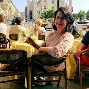 Woman sitting at an outdoor cafe in Milan, Italy, with a glass of white wine.