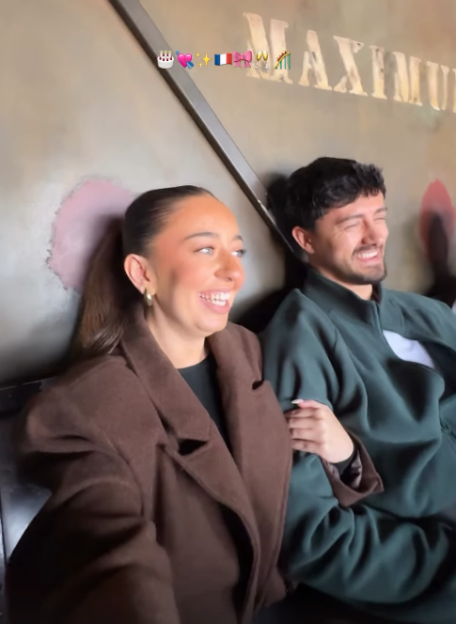Two people, a woman and a man, laughing while sitting side by side.