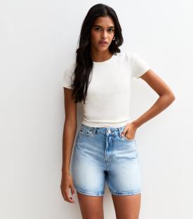 Woman wearing light blue denim shorts and a white shirt.