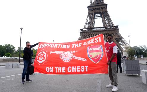 Two Arsenal fans in Paris holding a banner that says