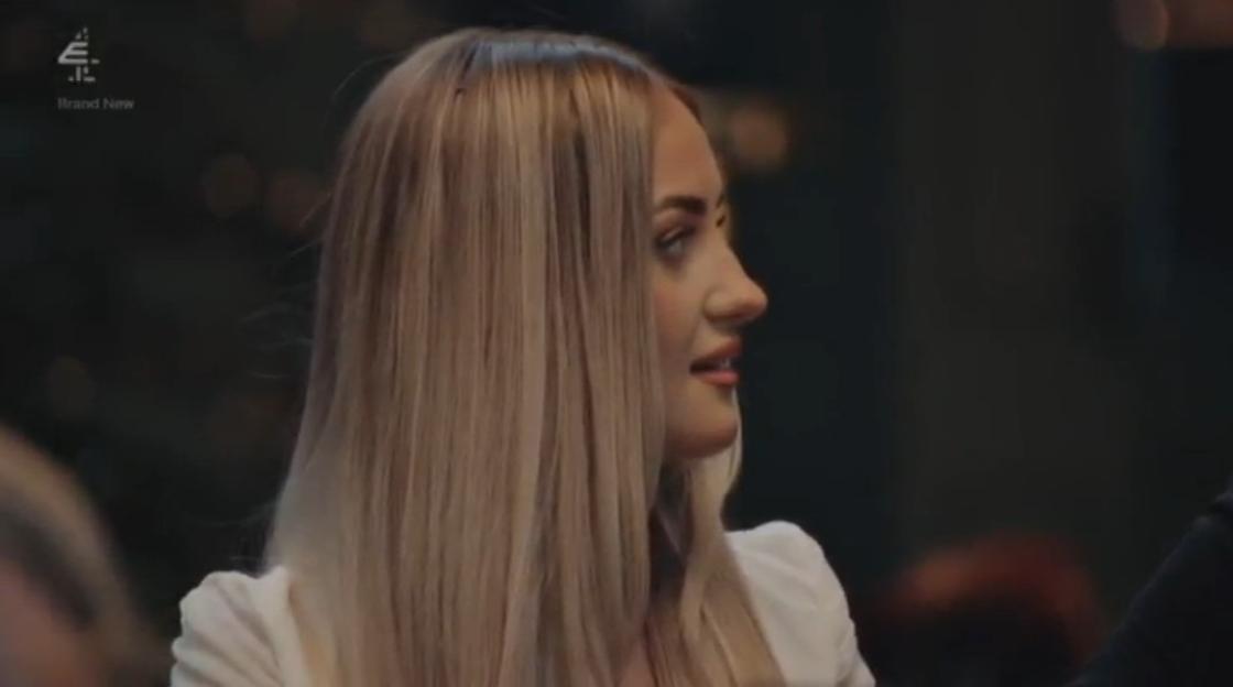 A blonde woman in a white jacket looks unimpressed.