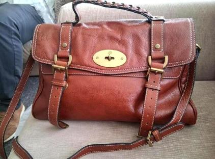 Brown leather satchel bag with brass hardware.