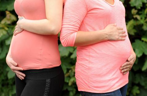 Two pregnant women standing side-by-side.