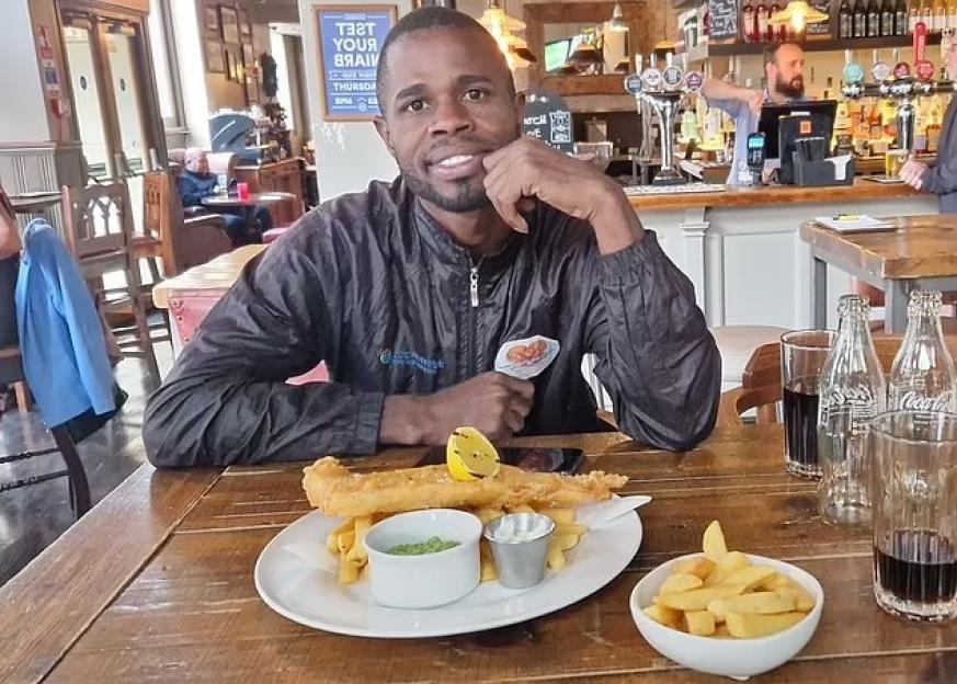Yostin Andres Mosquera, a Colombian national, smiles at a pub table with fish and chips.