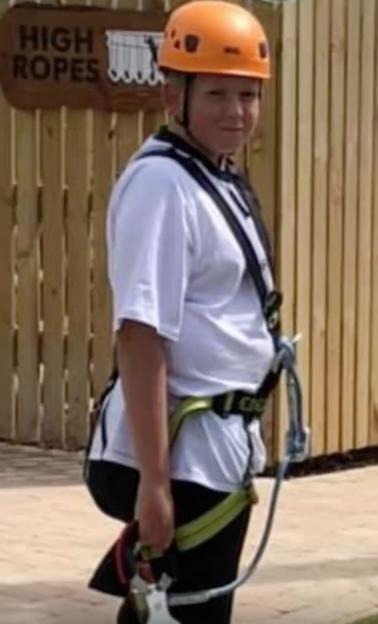 Photo of Kane Edwards wearing a climbing harness and helmet.