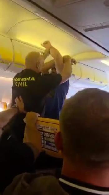 Police officers removing a disruptive passenger from a Ryanair plane.