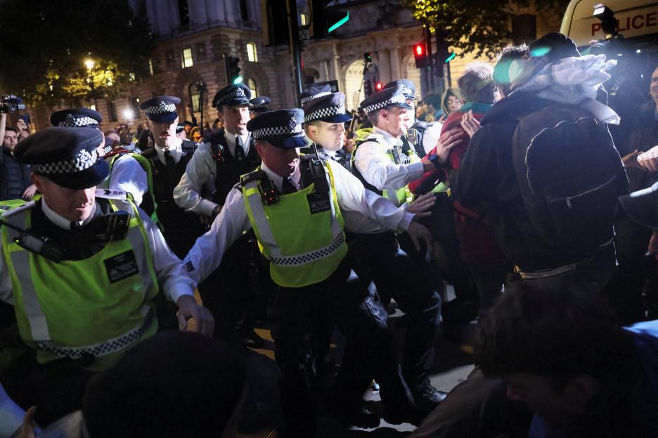 Police officers stopping people from marching during a protest in London.