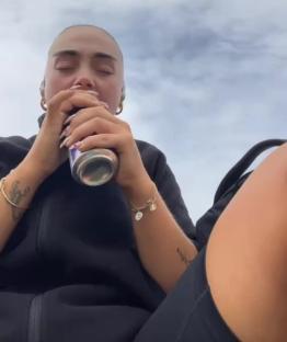 Woman with short hair carefully drinks from a can to avoid ruining her nails.