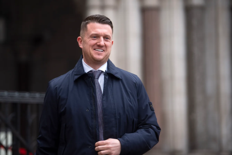Smiling man in a dark blue jacket and tie.