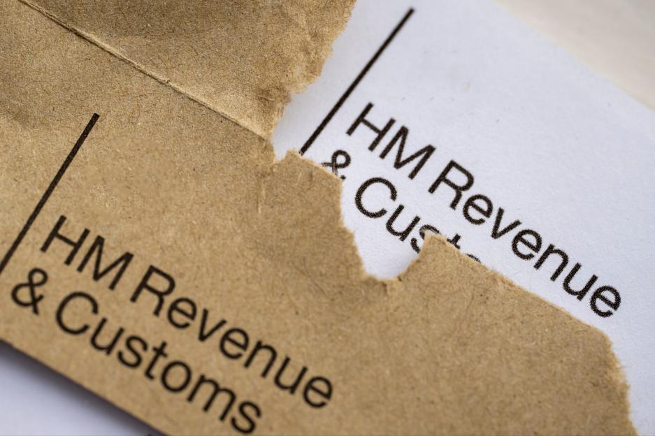 A torn brown envelope partially obscuring text that reads "HM Revenue & Customs" on the white letter inside.