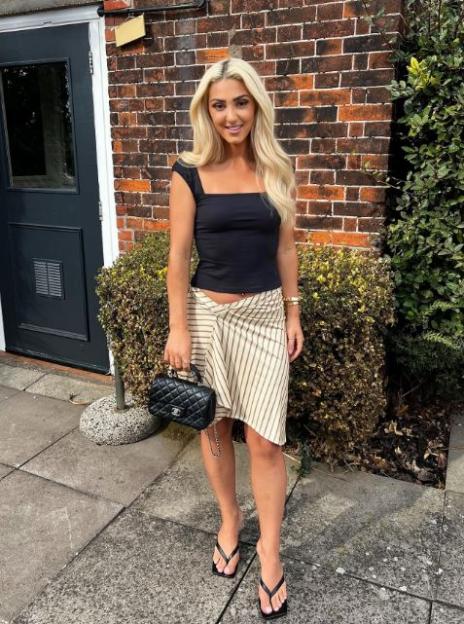 Bianca Petronzi in a black top and striped skirt, holding a Chanel bag.