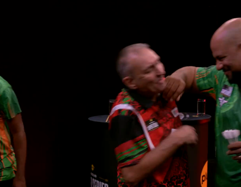 Two dart players embrace and laugh.